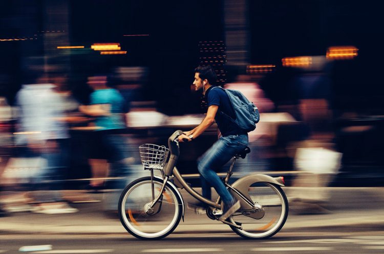 Man som cyklar förbi människor